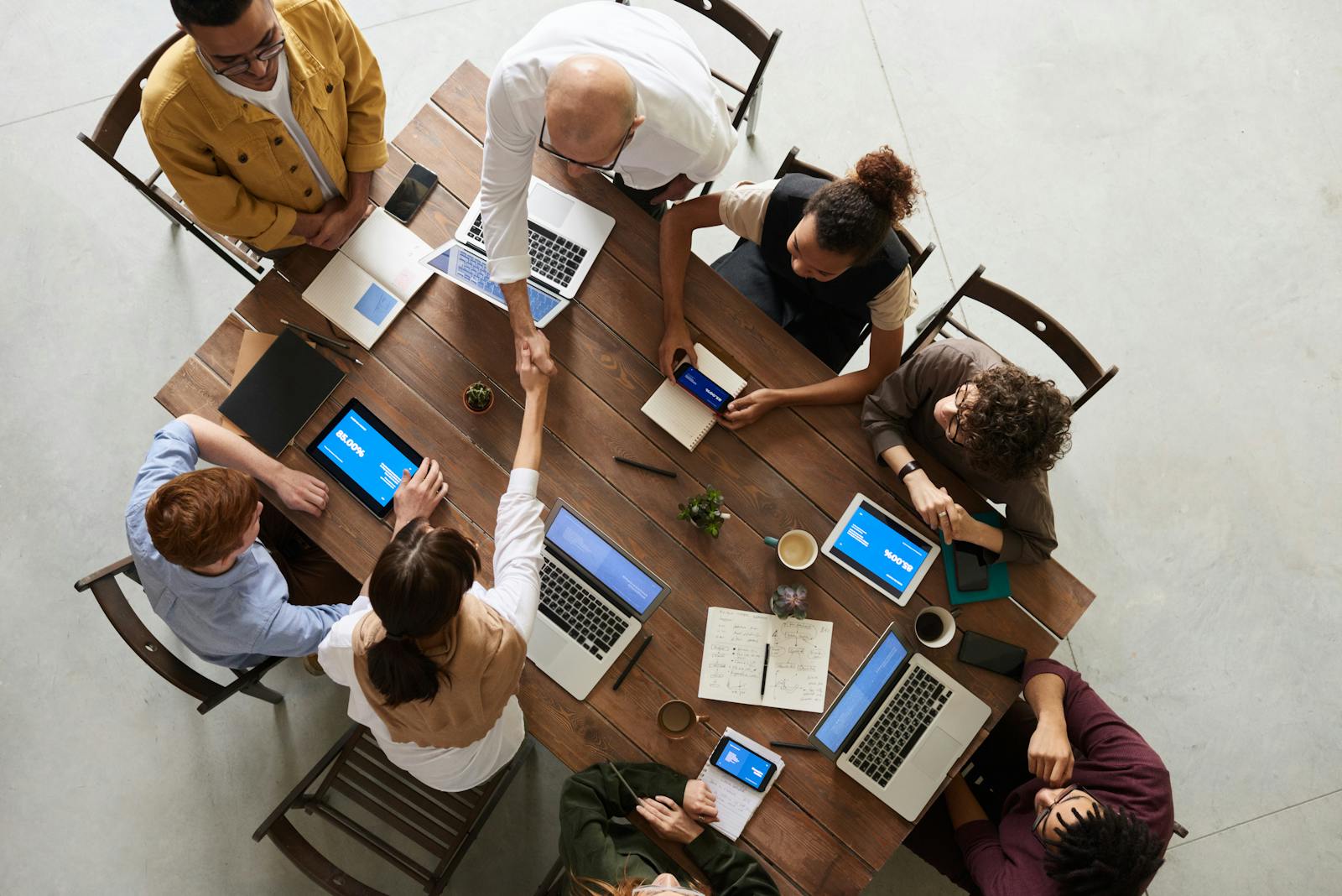 business, top view of a diverse team collaborating in an office setting with laptops and tablets, promoting cooperation.